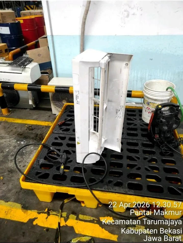 Casing unit indoor AC dibongkar di area kerja beralas spill pallet selama pekerjaan cuci AC di fasilitas Kuehne Nagel Bekasi