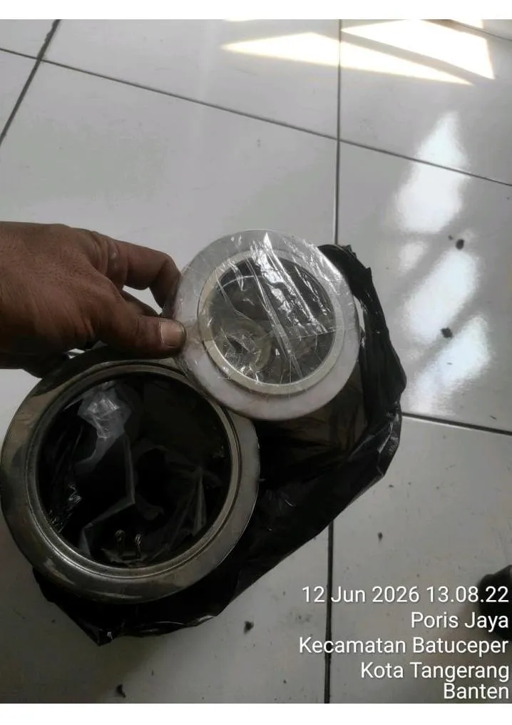 Kap fitting downlight E27 putih baru disiapkan untuk menggantikan dudukan lampu lama di area kerja fasilitas logistik