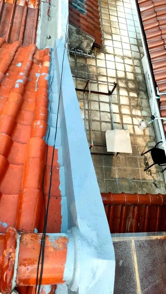 Lapisan waterproofing abu-abu menutup celah dinding atap dan sambungan di sepanjang jalur air