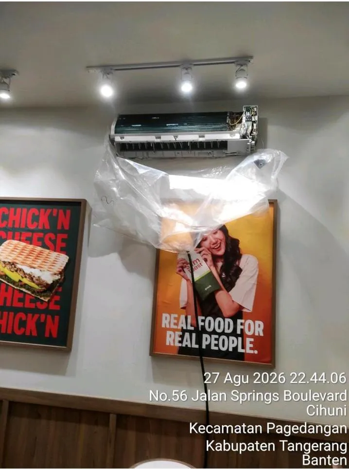 Casing indoor AC split dibuka sehingga sirip evaporator terlihat, dengan plastik penampung air terpasang saat pencucian unit